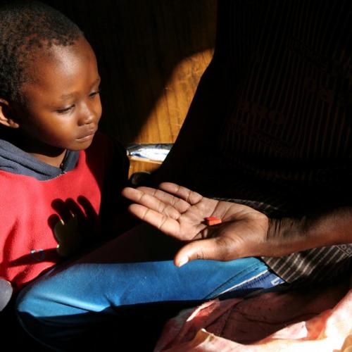 A man taking part in a BHP clinical trial for HIV/AIDs treatment shows medicine to his son, who is HIV-negative, in Gaborone, Botswana, on November 27, 2006. REUTERS/Joan Sullivan